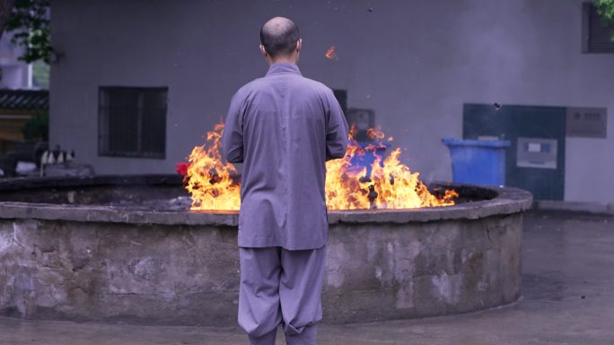寺庙燃烧的香炉前焚香祈福的僧人
