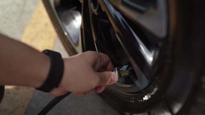 男机械师正在给汽车轮胎充气，给他的汽车轮胎充气控制器的轮胎充气。