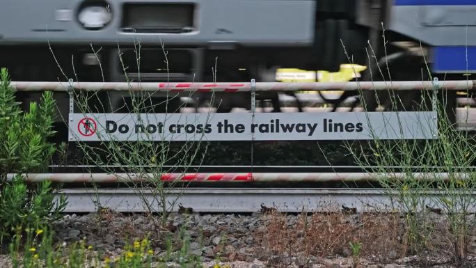 铁路线上悬挂“请勿横越”标志的旅客列车驶过站台
