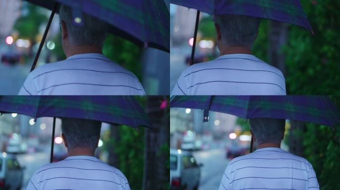 老人在雨天撑伞走在街上的背影。在下雨的下午，在城市环境中散步的老年人