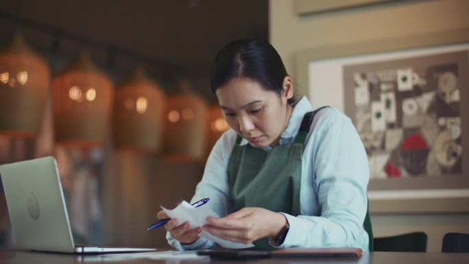 咖啡店老板在查看财务账单和笔记本电脑的同时查看咖啡店的财务状况