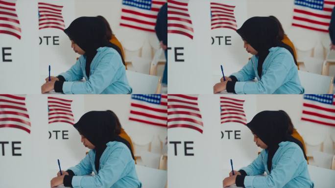 戴头巾的穆斯林妇女在美国投票站的选票上写字