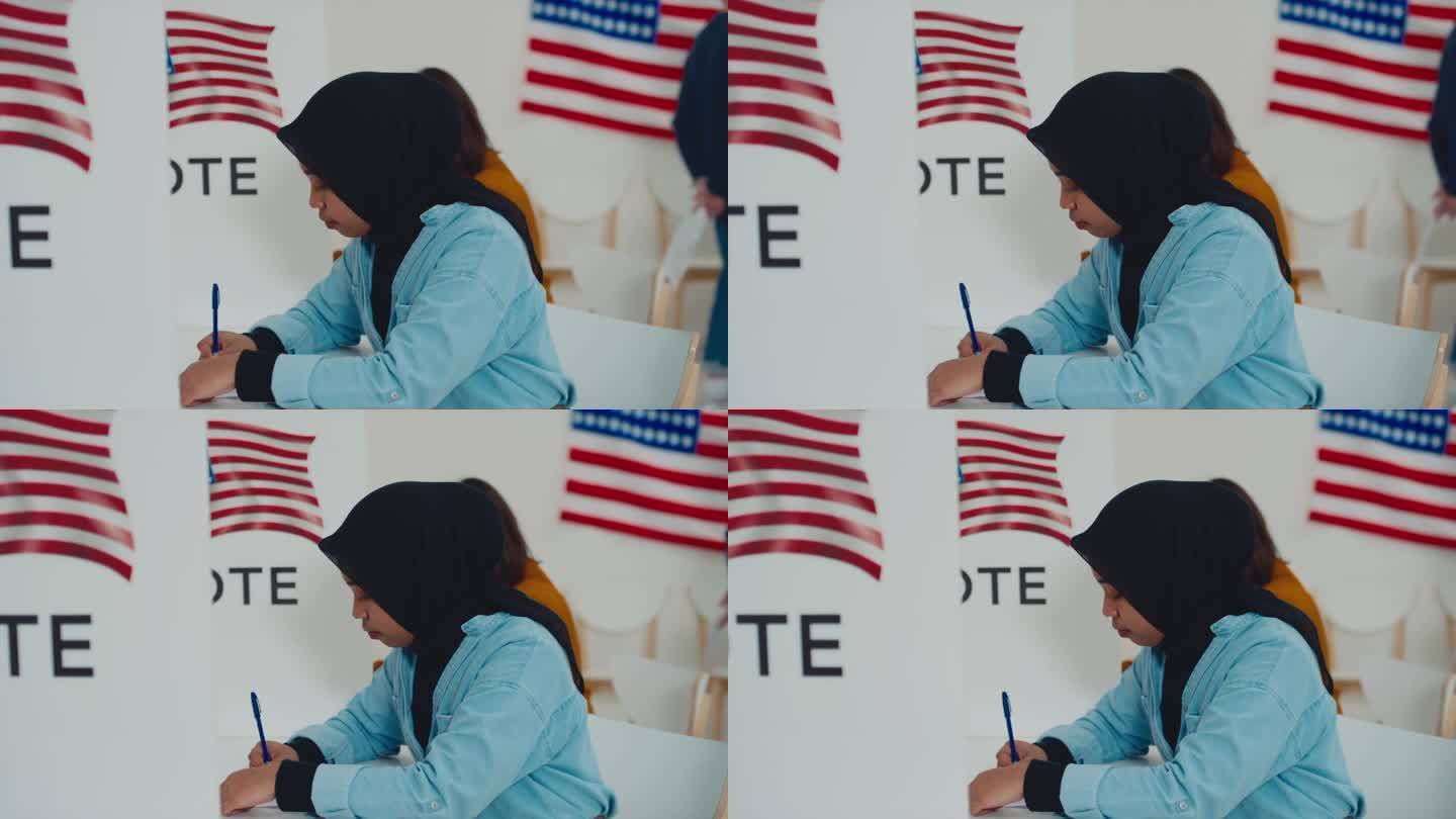 戴头巾的穆斯林妇女在美国投票站的选票上写字