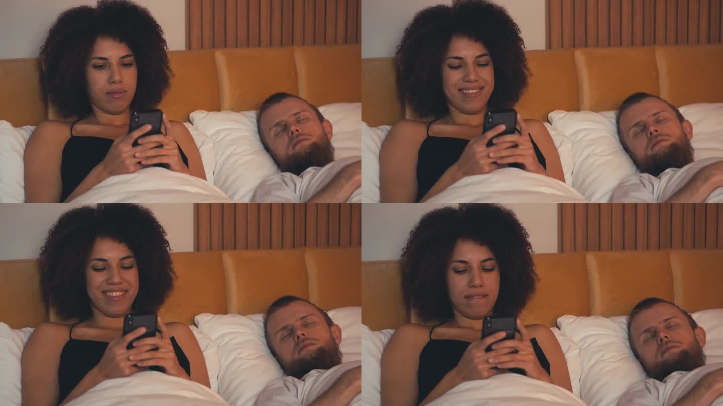 非裔美国女人和丈夫躺在床上发短信，出轨