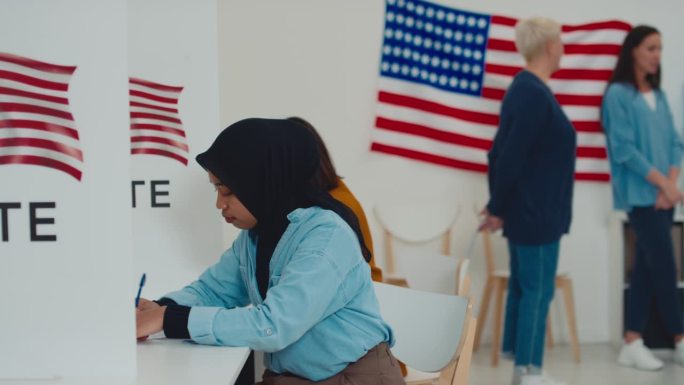 戴头巾的穆斯林妇女在选举区的投票站填写选票