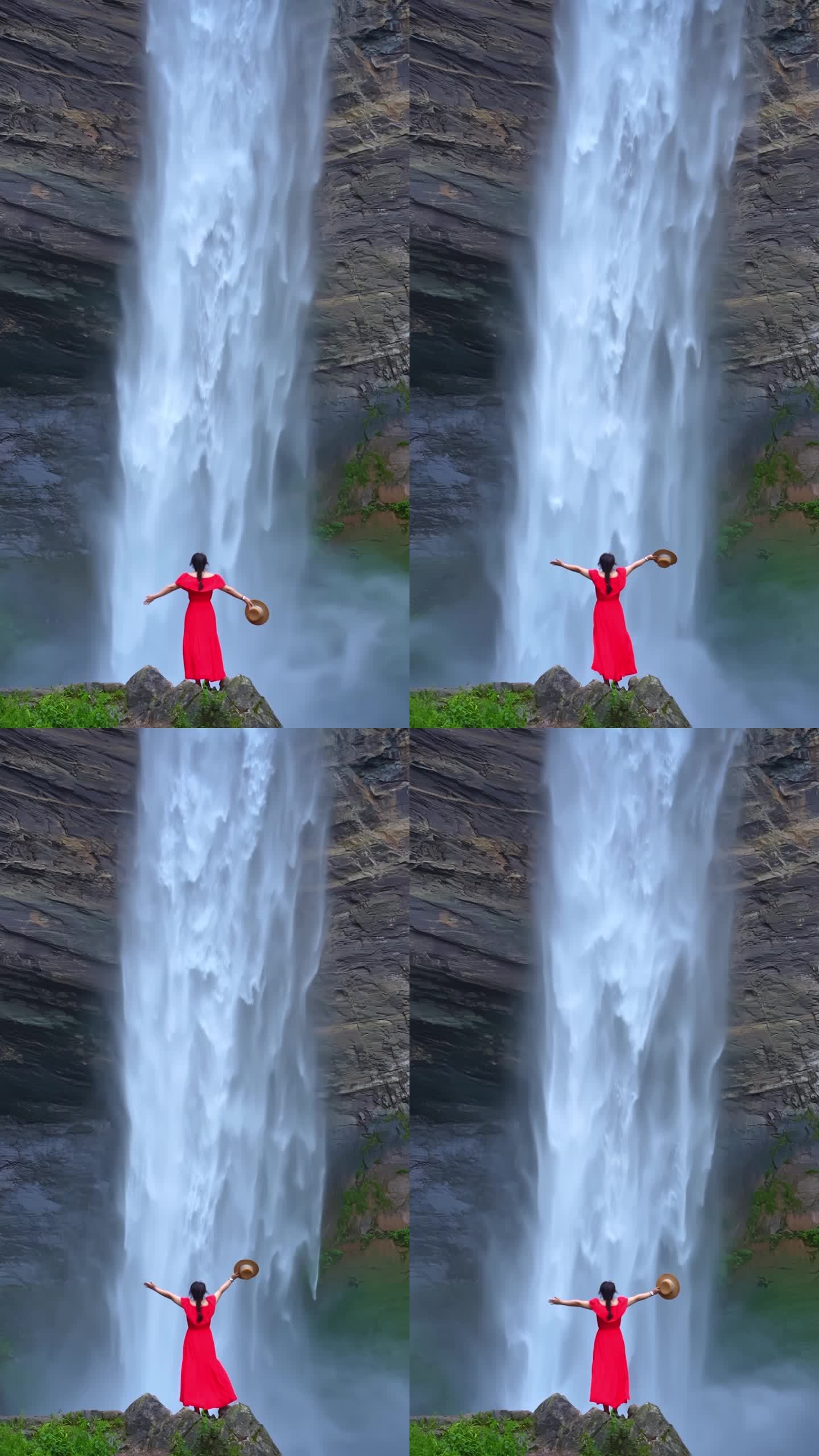 贵州夏天天然瀑布下的红色裙子女人