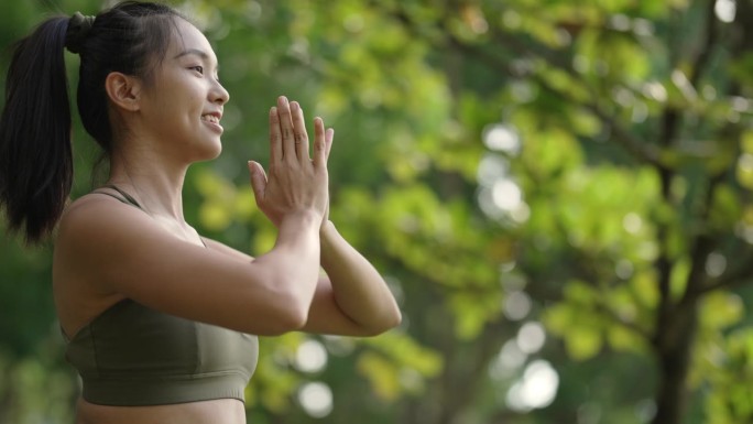 周末早上，一名亚裔华裔女子在公园里练习瑜伽