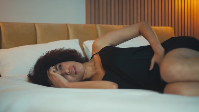 非裔美国妇女躺在床上遭受腹痛，经期痉挛