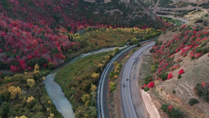 一架缓慢移动的无人机拍摄的6号高速公路蜿蜒穿过犹他州西班牙叉附近的山脉，在一个秋天的下午，颜色开始变