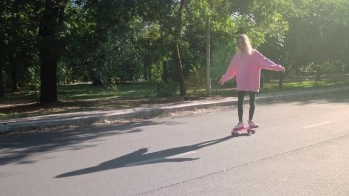 金发女郎在公园里学滑板