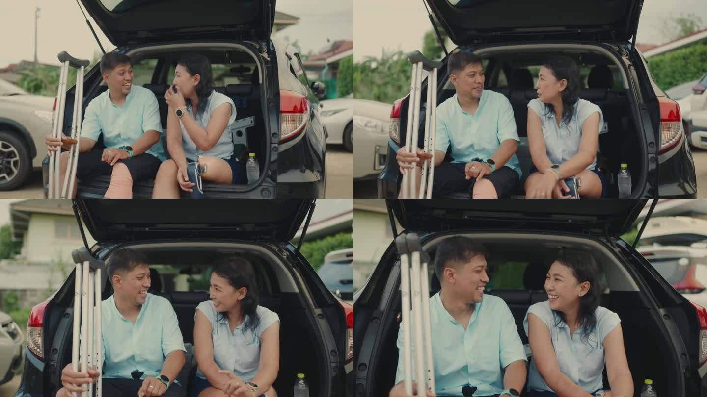 亚洲残障夫妇在汽车行李箱中微笑交谈-一起拥抱生活