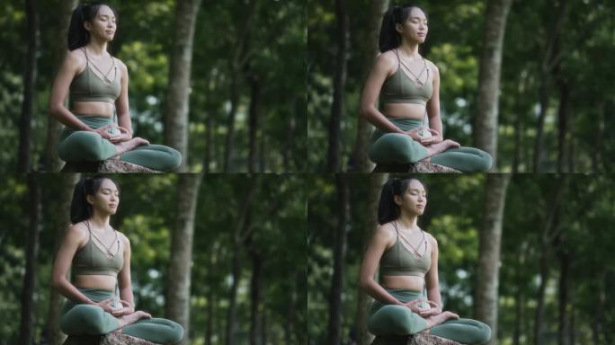 周末早上，一名亚裔华裔妇女在公园里冥想练习瑜伽