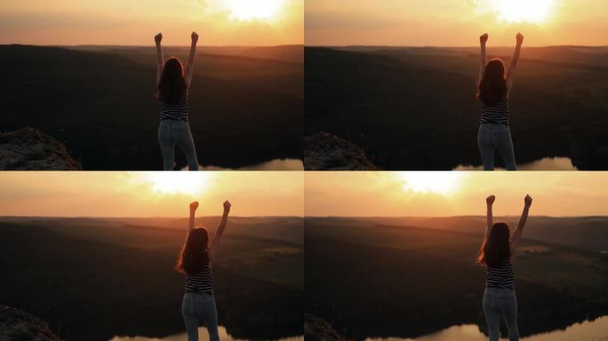 快乐苗条的女孩站在夕阳山，举起双臂，欣赏风景
