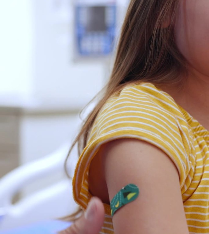 护士将创可贴贴在刚接种疫苗的女孩身上