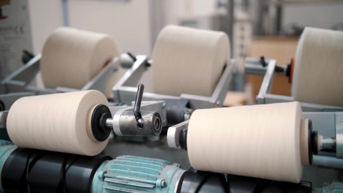 线生产。纺织工厂。纺纱生产。纱线制作工艺。纺织厂设备纱线线的特写线轴。