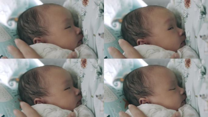 亚洲新生儿在吮吸完妈妈的乳汁后，快乐地躺在妈妈的怀里。
