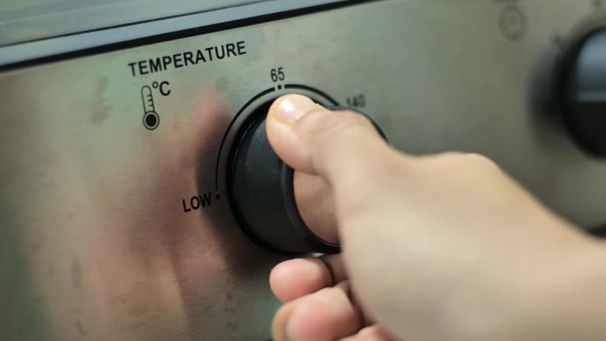 一只手把微波炉的温度旋钮从低温转到高温。用中镜头和手持拍摄。