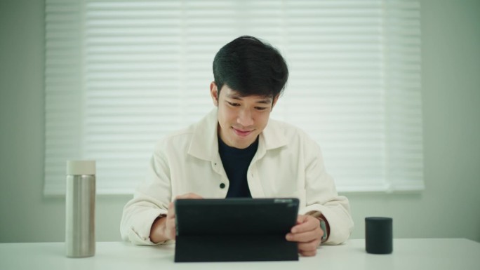男子使用数码平板电脑和蓝牙扬声器。