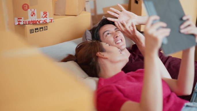 亚洲年轻夫妇躺在地板上集思广益，想买什么东西来装饰他们的房子。
