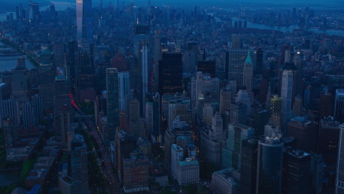 电影航拍夜景捕捉纽约市摩天大楼。全景直升机飞越华尔街金融区历史悠久的城市建筑的屋顶和尖塔