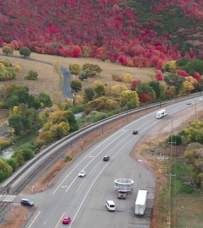 一架缓慢移动的无人机拍摄的6号高速公路蜿蜒穿过犹他州西班牙叉附近的山脉，在一个秋天的下午，颜色开始变