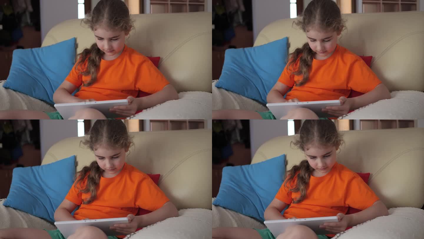 可爱的女孩在平板电脑上玩游戏的肖像，在客厅放松。孩子浏览社交媒体。孩子坐在沙发上使用平板电脑，在家上