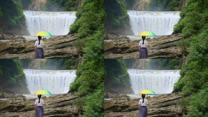 贵州夏天一个女人打着伞在观看瀑布