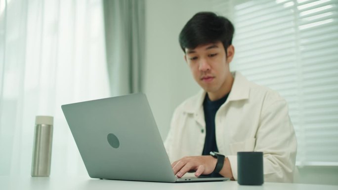 男人正在用笔记本电脑和蓝牙扬声器工作。