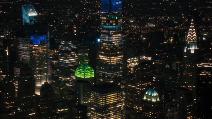 从空中俯瞰纽约曼哈顿市中心的建筑。从直升机上拍摄的商业区全景画面。城市景观，晚上办公室里有灯的建筑