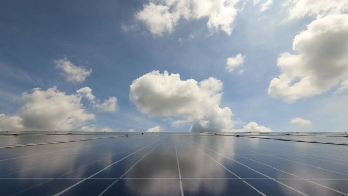 云从太阳能农场的太阳能电池板上掠过，展示了可重复使用和绿色能源的概念。