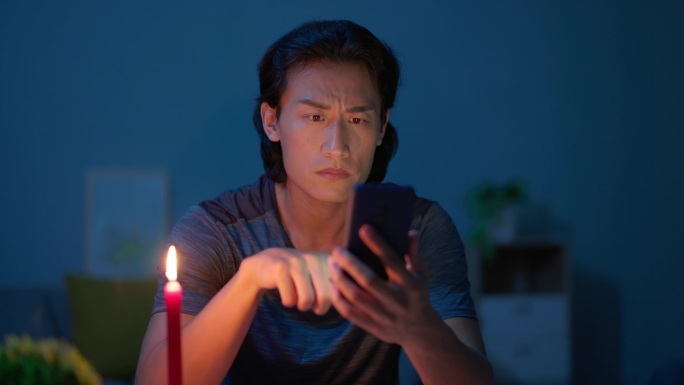 停电的亚洲人停电点蜡烛烛火照明深夜玩手机