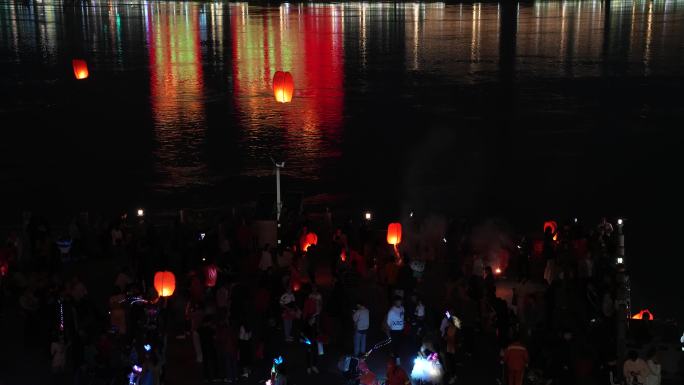 节假日夜晚城市江边燃放孔明灯祈福的人群