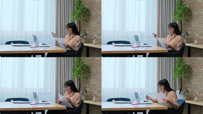 中年商务女性在工作场所使用笔记本电脑进行虚拟视频会议