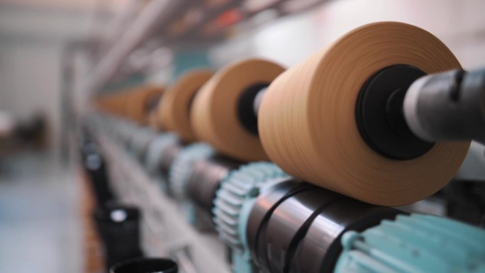 纱线制作工艺。线生产。纺织厂设备。纺织工厂。纺纱生产。近距离的纱线线轴。