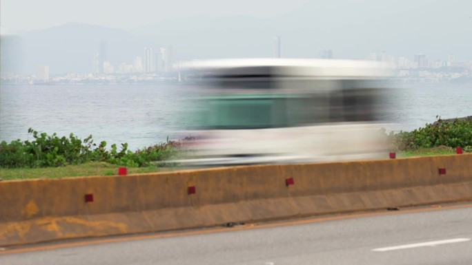 高速公路的时间流逝，汽车和卡车在前景中快速行驶。背景是圣多明各市中心和山脉。人们在大城市里努力生活和