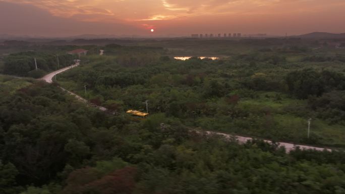 夕阳晚霞下行驶在乡间小路上的黄色校车巴士