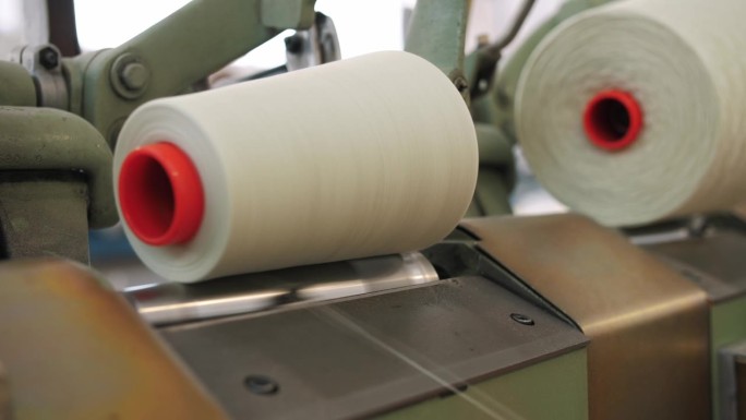 纺纱生产。纱线制作工艺。纺织厂设备。线生产。纺织工厂。近距离的纱线线轴。