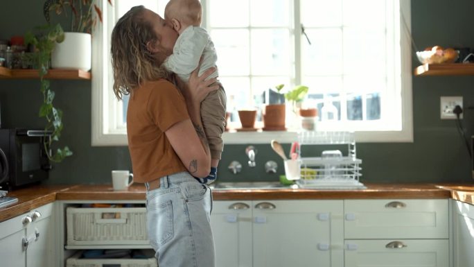 妈妈，孩子和在厨房跳舞作为一个家庭一起爱，信任或支持他们的家。家庭，孩子和一个女人在公寓里亲吻她的婴