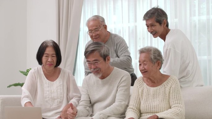 一群快乐的亚洲老人男女用笔记本电脑进行视频通话。