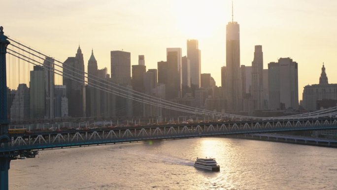 空中电影无人机镜头在曼哈顿大桥与曼哈顿下城摩天大楼的城市景观。专注于布鲁克林悬索桥建筑。美丽的夕阳与