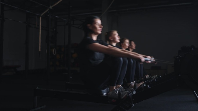 现代健身中心，一群运动女性在划船机上进行高强度锻炼