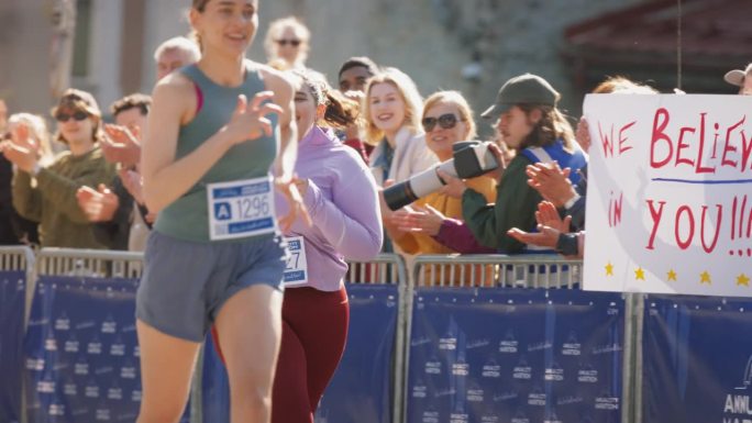 大码微笑女跑者展示意志力参加城市马拉松慢镜头。友好的参赛者向观众挥手，决心到达终点线