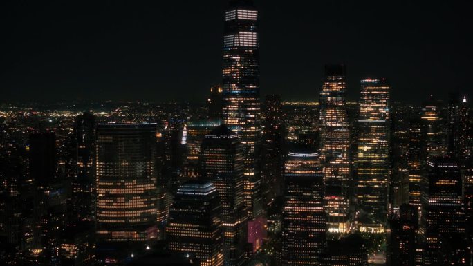 空中直升机电影夜景全景与一个世界贸易中心摩天大楼和充满活力的城市景观。带有室内灯光的美丽办公大楼
