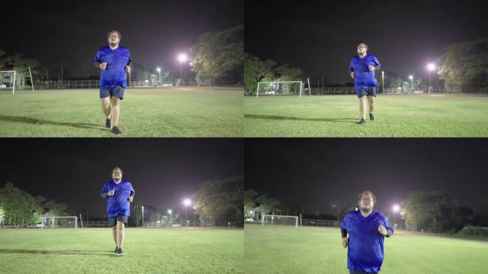 为了减肥，一个非常胖的亚洲男人在公园的草坪上继续他的跑步运动，尽管已经很晚了。