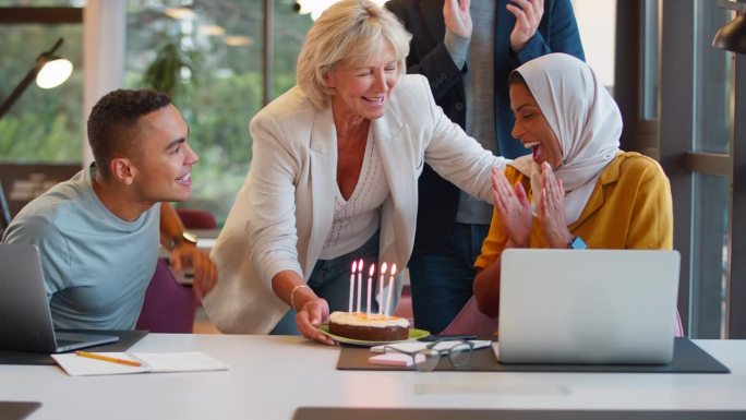 员工用蛋糕庆祝戴头巾女同事生日