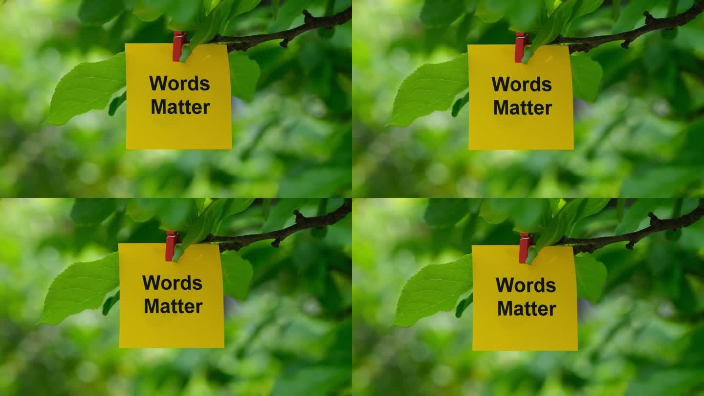 一张黄色的纸条，上面写着“文字很重要”，用衣服别针别在树枝上