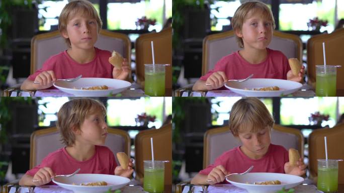 小男孩正在咖啡馆里吃饭。他正在吃煎饺子。