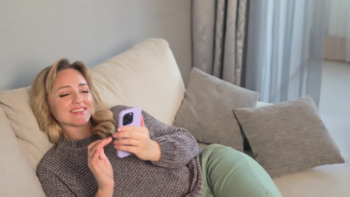 女人在沙发上放松时使用智能手机