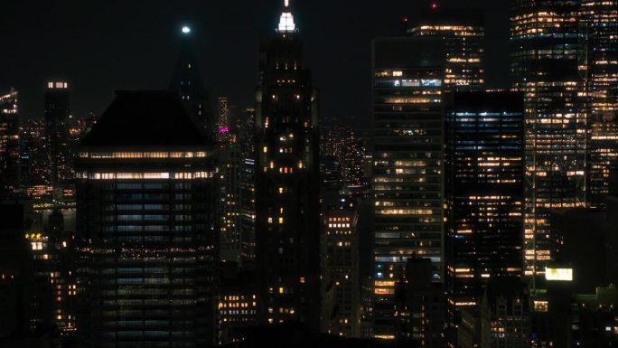 直升机夜游纽约市。鸟瞰图与一个风景如画的照明办公大楼，风景与曼哈顿摩天大楼全景