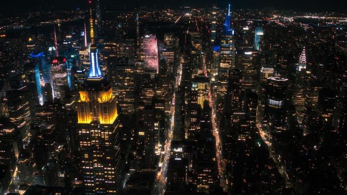 帝国大厦塔尖夜景和顶层游客观景台。纽约市商业中心。曼哈顿中城建筑奇观的直升机镜头